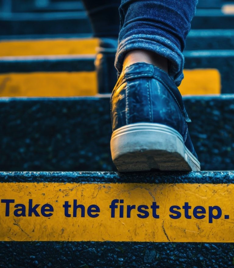 Take the first step. Jemand geht die Treppe nach oben. Auf einer Stufe steht "Take the first step." Die Person ist dabei den Weg in die richtige Richtung gehen.